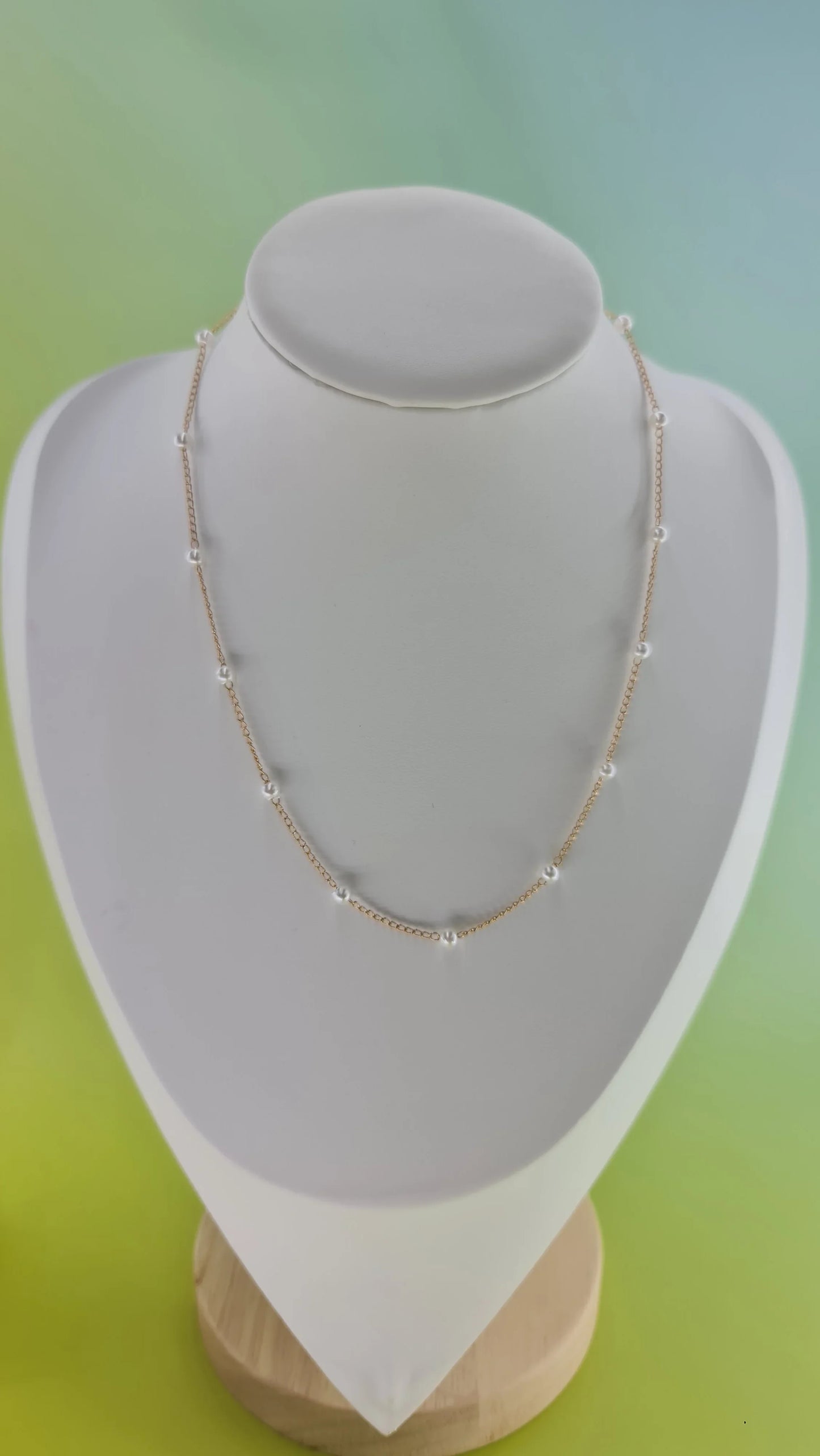 Collier doré délicat avec petites perles blanches, bijou femme 974 Réunion, fond dégradé.