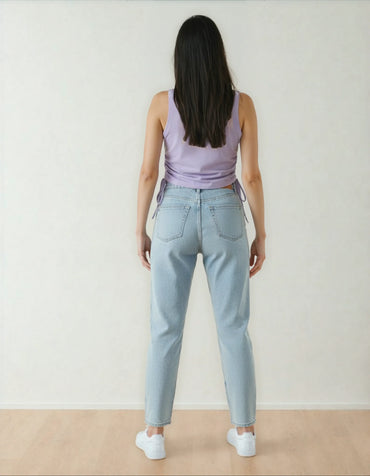 Femme de dos portant un jeans clair et un débardeur lavande, sol bois, 974 Réunion