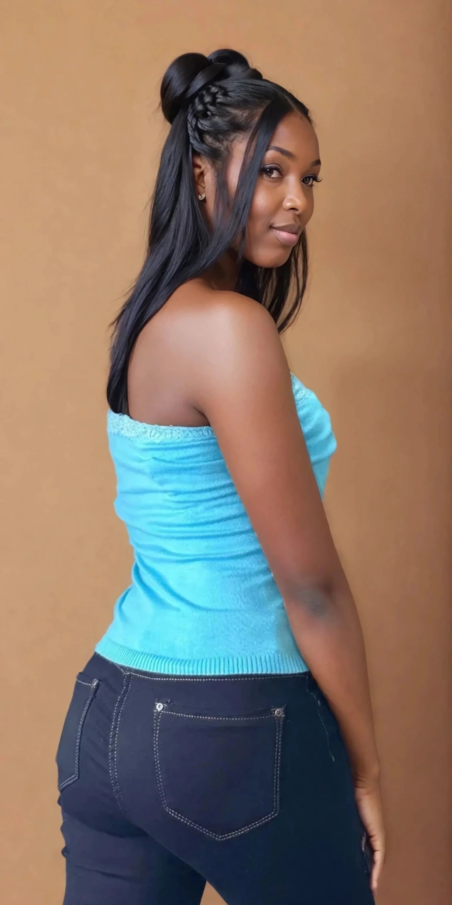 Femme portant un bustier turquoise et un jean, mode tendance 974 Réunion, fond neutre.