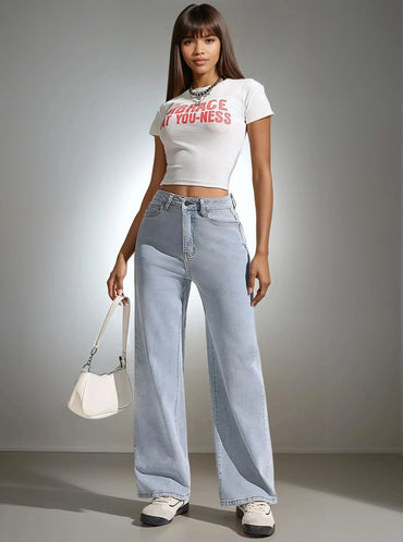 Femme portant un crop top blanc, jean large et sac à main, tendance 974 Réunion.