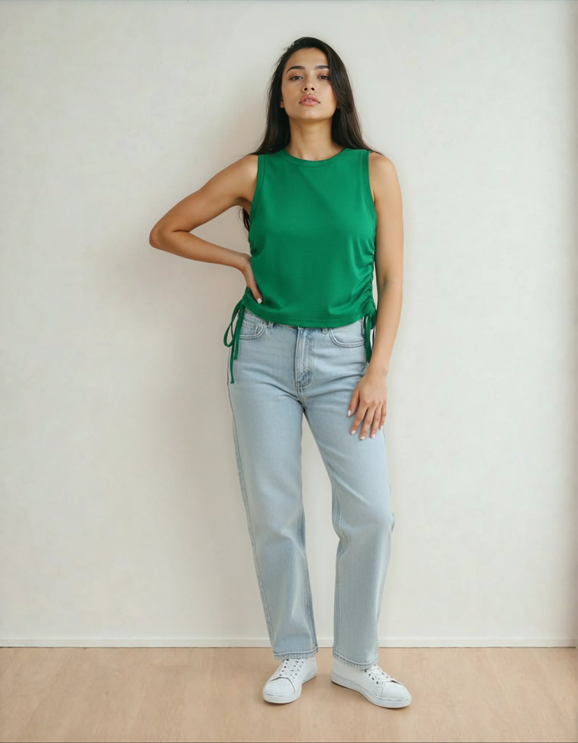 Femme debout en jean clair, débardeur vert et baskets blanches, mode 974 La Réunion