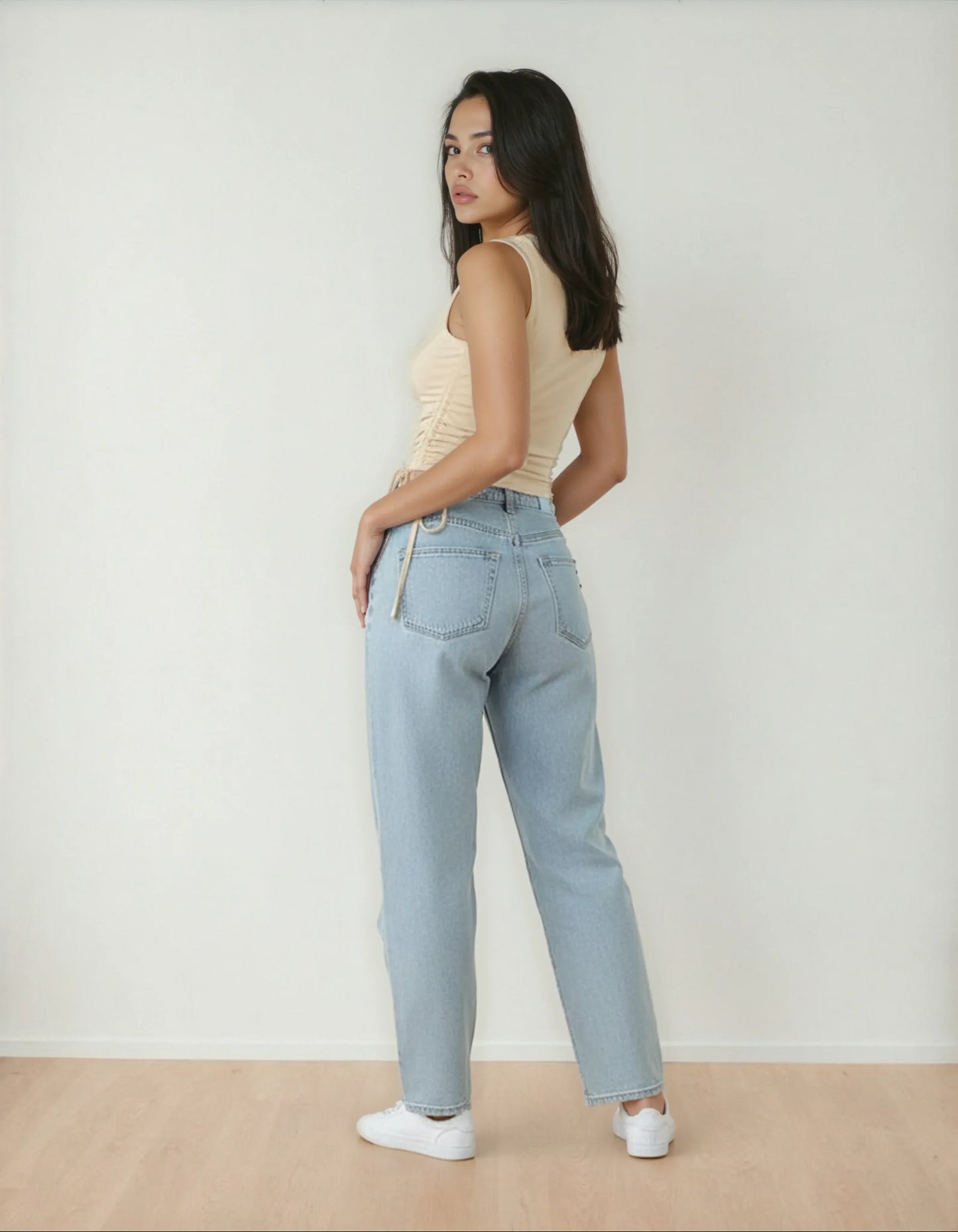 Femme portant un jean taille haute bleu clair et débardeur beige, mode 974 Réunion
