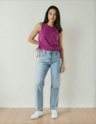 femme posant en débardeur violet, jean clair et baskets blanches, mode 974 Réunion