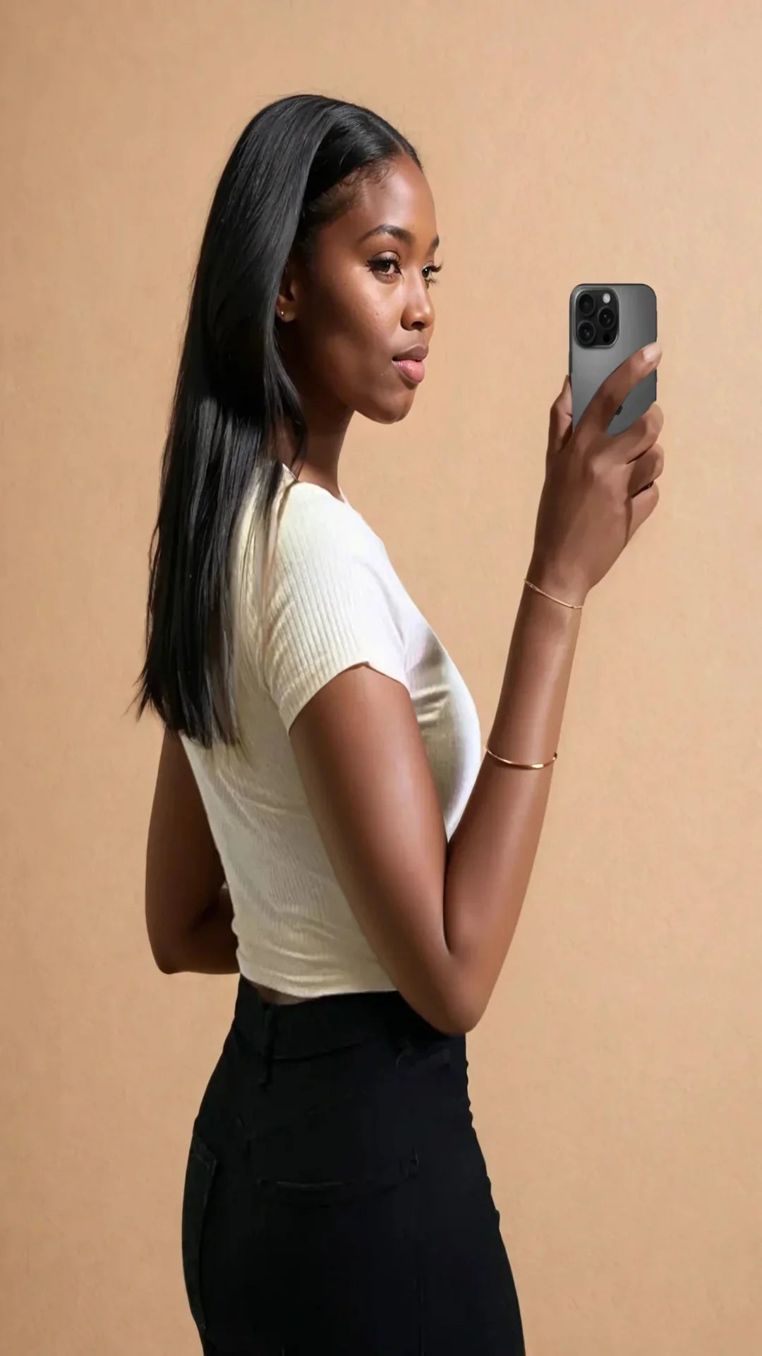 Femme portant un top court blanc et pantalon noir, selfie mode 974 Réunion, fond beige.